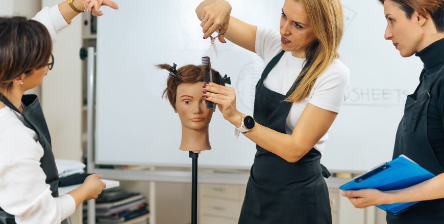 Professional Hairdresser Teaching Adult Students How to Use Hairdressing Scissors during Course