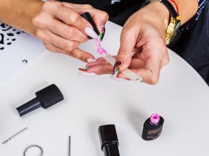 Worker in a nail salon, paints artificial extension nails at the workplace. View from above. Photo taken in Russia, in the city of Orenburg